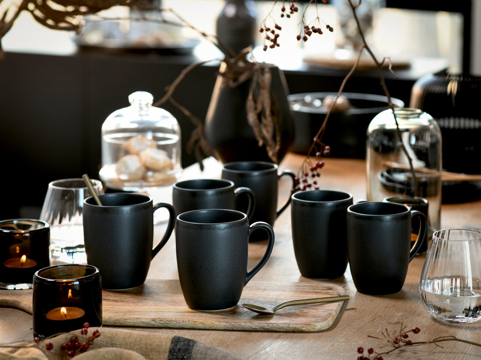 Creatable Kaffeebecher 6-tlg SOFT TOUCH Mehrere matte schwarze Keramikbecher auf einem gedeckten Holztisch mit Gläsern, Kerzen und Dekoration, fotografiert aus leicht erhöhter Frontperspektive