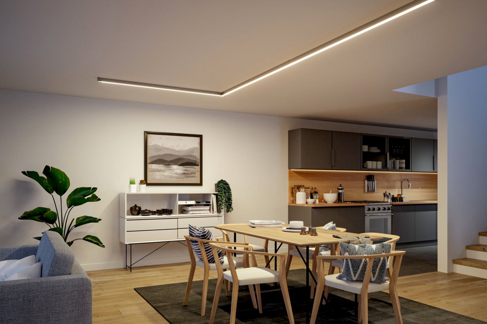 Moderner Ess- und Küchenbereich mit indirekten LED-Deckenlinien, Holzesstisch und Stühlen sowie grauer Einbauküche, aufgenommen aus leicht erhöhter Perspektive im Weitwinkel.