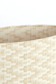 Nahaufnahme eines beige gemusterten Lampenschirms mit gewebter Textur, seitliche Perspektive.