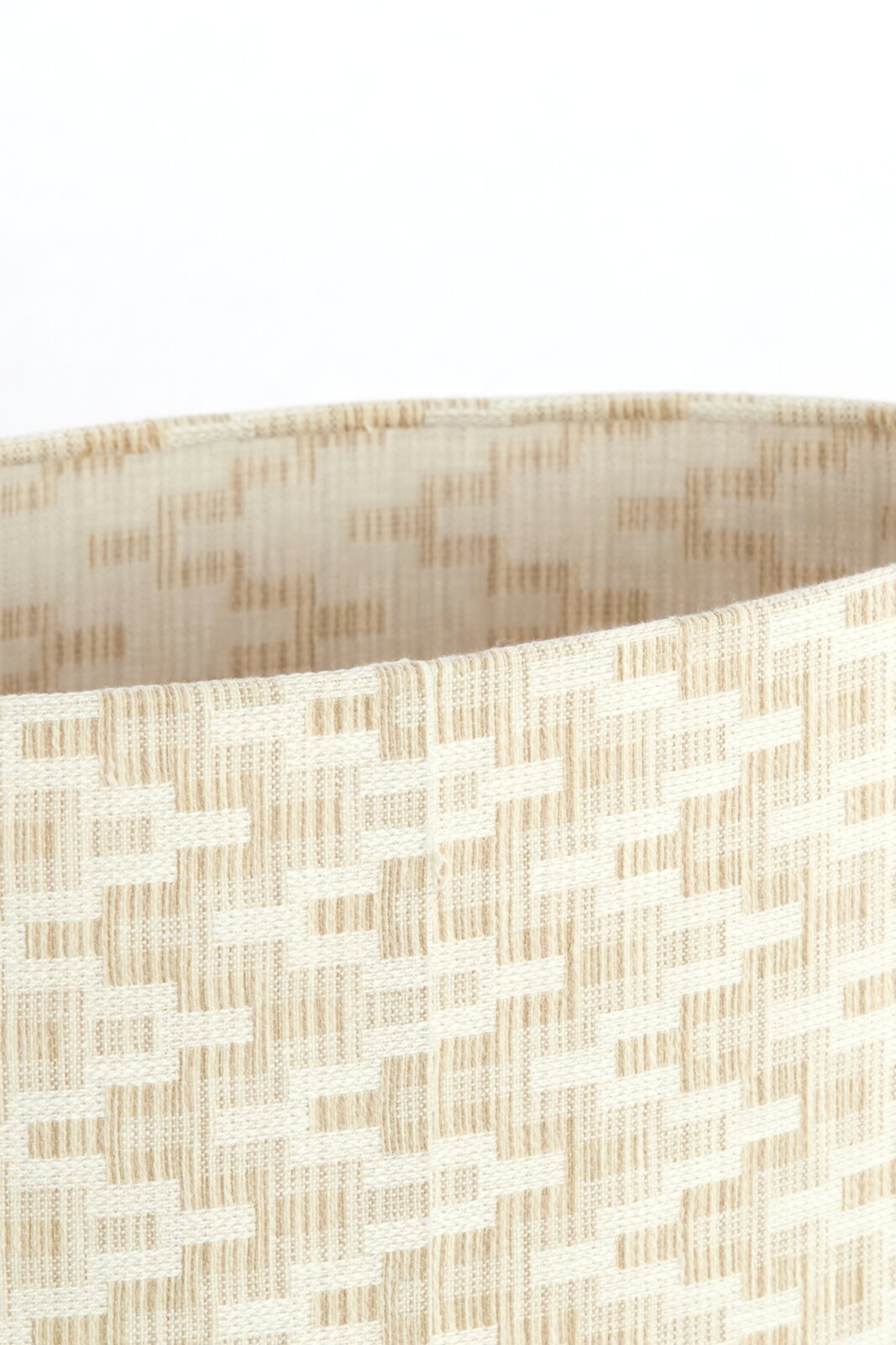 Nahaufnahme eines beige gemusterten Lampenschirms mit gewebter Textur, seitliche Perspektive.