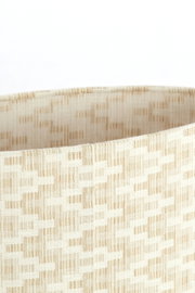 Nahaufnahme eines beige gemusterten Lampenschirms mit gewebter Textur, seitliche Perspektive.