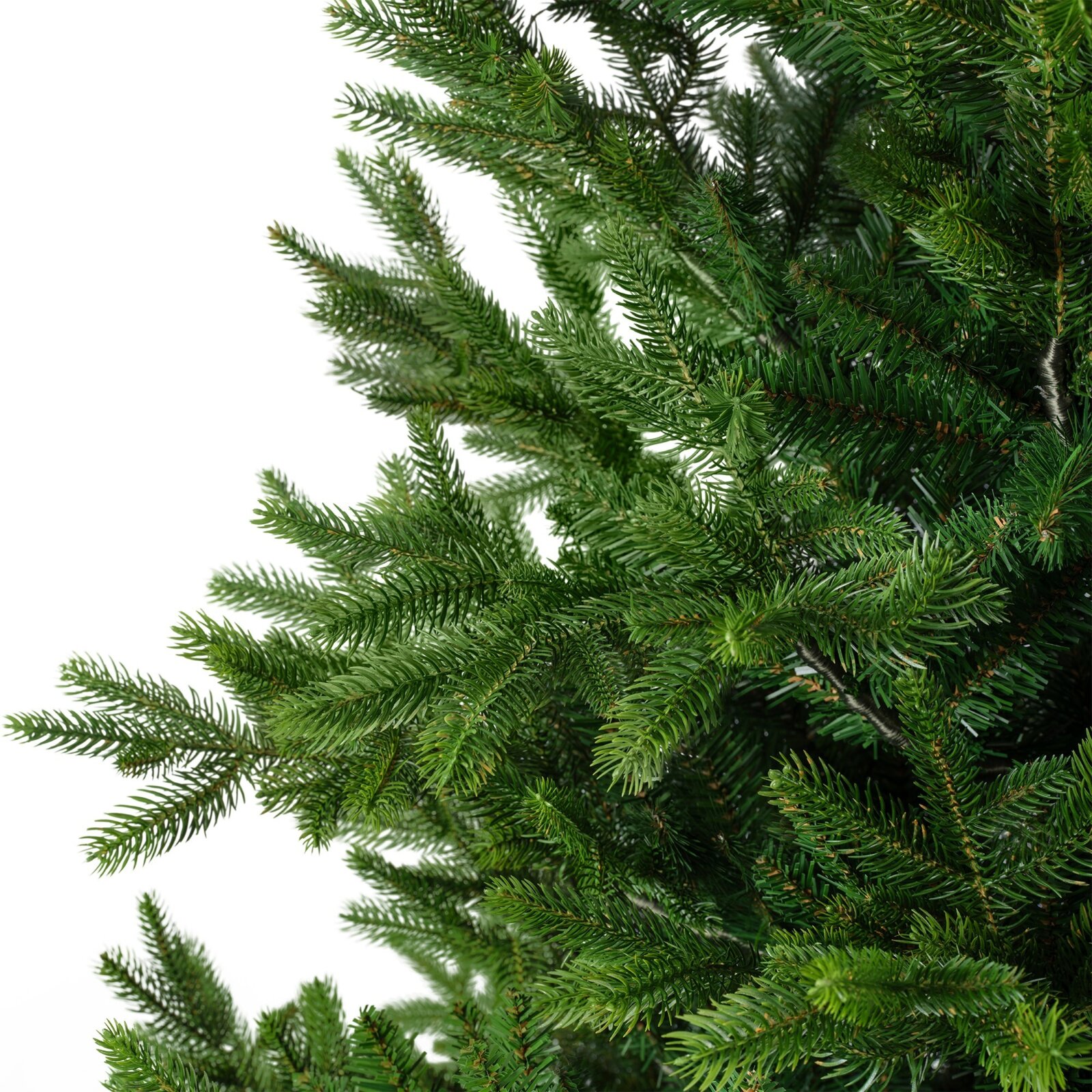 Detailansicht aus seitlicher Perspektive auf die dichten, naturgetreu gestalteten grünen Zweige eines künstlichen Weihnachtsbaums vor weißem Hintergrund