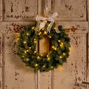 Weihnachtskranz mit Lichtern und Schleife, frontal an einer Holztür aufgehängt