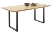 Moderner Esstisch aus Holz mit Metallbeinen, seitliche Perspektive, dekoriert mit Geschirr und Olivenölflasche.