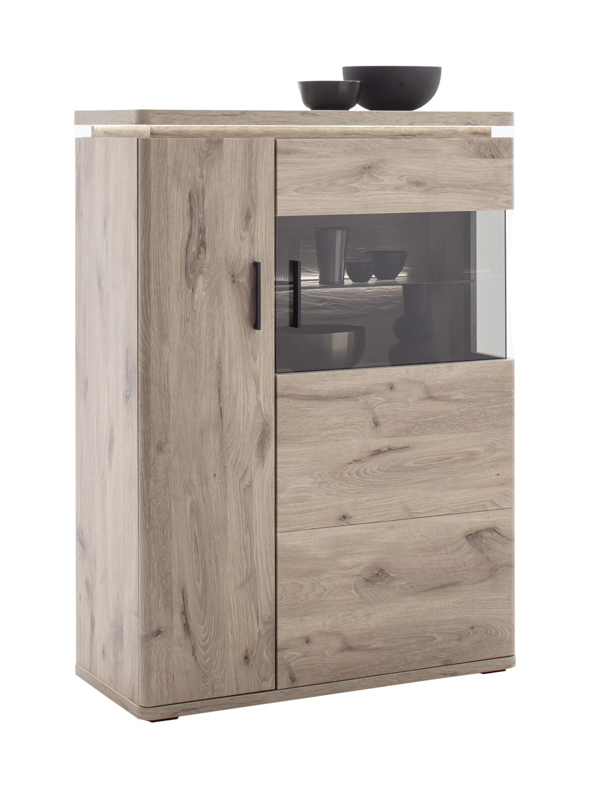 Moderne Highboard/Vitrine aus heller Eiche-Optik mit Holzmaserung, links Tür und rechts Glasfront mit schwarzen Griffen, fotografiert in leicht schräger Vorderansicht vor weißem Hintergrund.