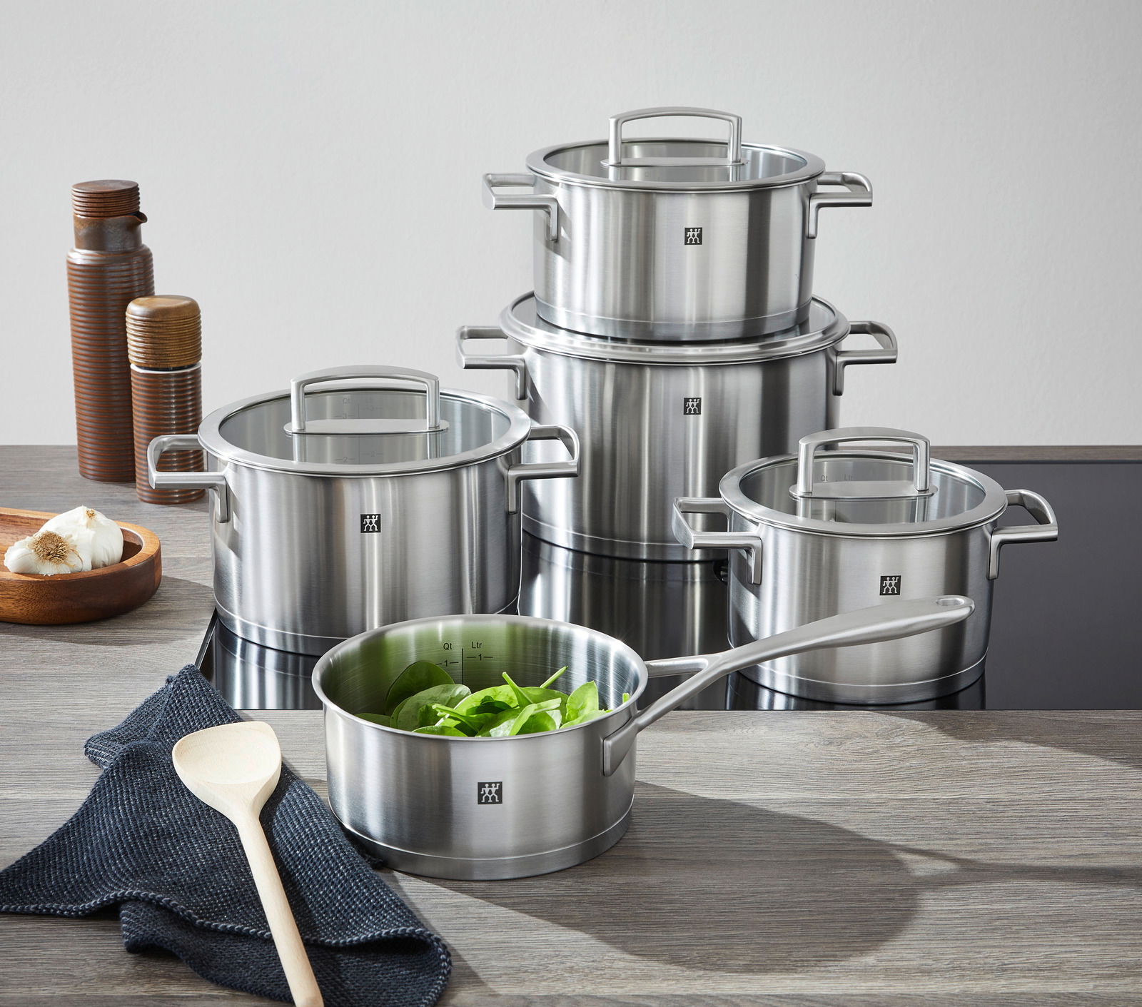 Fünfteiliges Topfset Vitality aus Edelstahl, bestehend aus verschiedenen Töpfen mit Glasdeckeln, auf einer Küchenarbeitsplatte von vorne fotografiert.