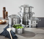 Fünfteiliges Topfset Vitality aus Edelstahl, bestehend aus verschiedenen Töpfen mit Glasdeckeln, auf einer Küchenarbeitsplatte von vorne fotografiert.