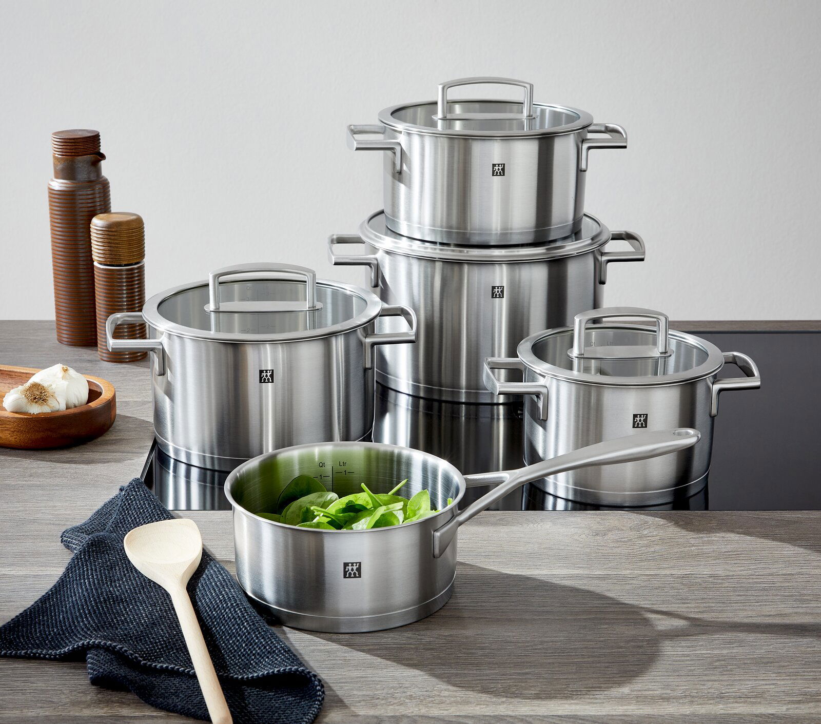 Fünfteiliges Topfset Vitality aus Edelstahl, bestehend aus verschiedenen Töpfen mit Glasdeckeln, auf einer Küchenarbeitsplatte von vorne fotografiert.