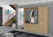 Moderne Kommode aus Holz mit Schubladen und Kleiderstange, frontal fotografiert in einem stilvollen Wohnraum mit Treppe und Pflanze.