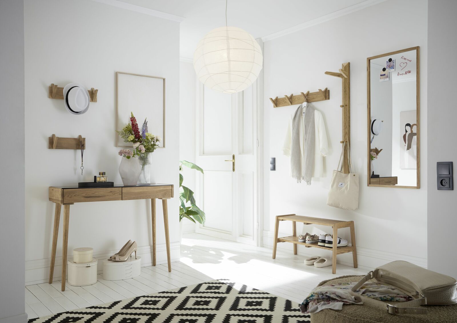 Moderner Eingangsbereich mit Holz-Garderobenmöbeln, darunter eine Garderobenbank, Hakenleisten und ein Spiegel, aus der Perspektive des Raumes fotografiert.