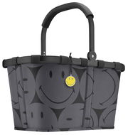 Grauer Einkaufskorb mit schwarzen Smiley-Motiven und einem gelben Smiley-Anhänger, seitliche Perspektive