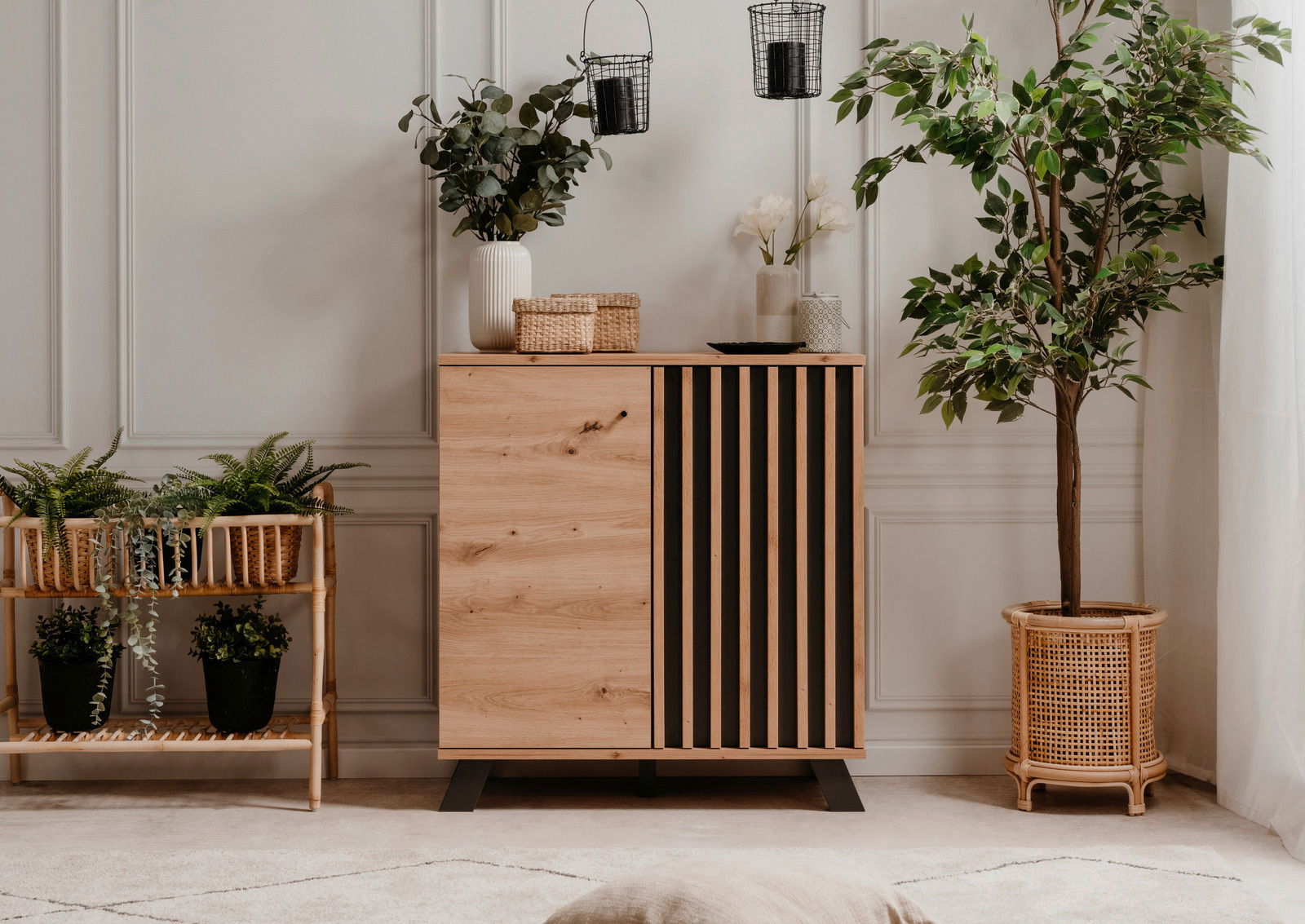 Moderne Kommode aus Holz mit vertikalen schwarzen Streifen, umgeben von Pflanzen, aus frontaler Perspektive fotografiert.