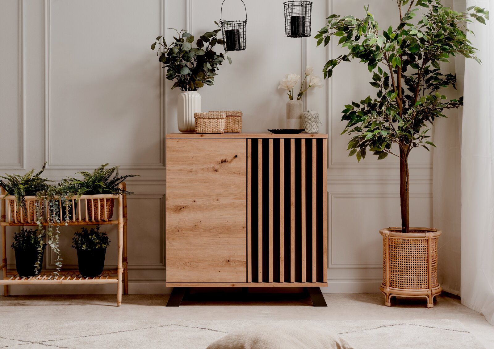 Moderne Kommode aus Holz mit vertikalen schwarzen Streifen, umgeben von Pflanzen, aus frontaler Perspektive fotografiert.