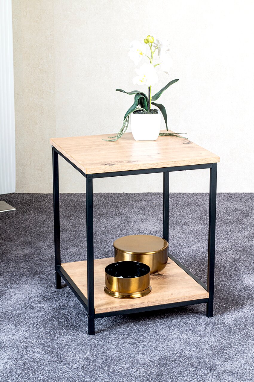 Quadratischer Beistelltisch mit Holzoptik-Platte und schwarzem Metallgestell, unten zweite Ablage mit goldfarbenen Dosen, oben weiße Orchidee; Aufnahme in leichter Schrägansicht von vorne.