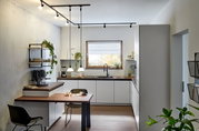 Moderne Küche mit Schienenspot-Beleuchtung an der Decke, Blick von der Seite auf die Arbeitsfläche und den Esstisch.