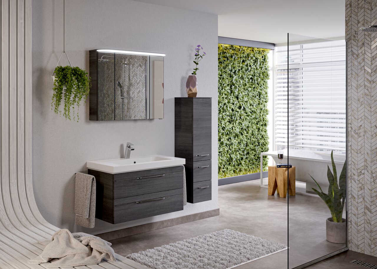 Moderne Badezimmeransicht mit einem hängenden Badblock in dunklem Holzton, Waschbecken mit Spiegel und grüner Pflanzenwand im Hintergrund, seitliche Perspektive.
