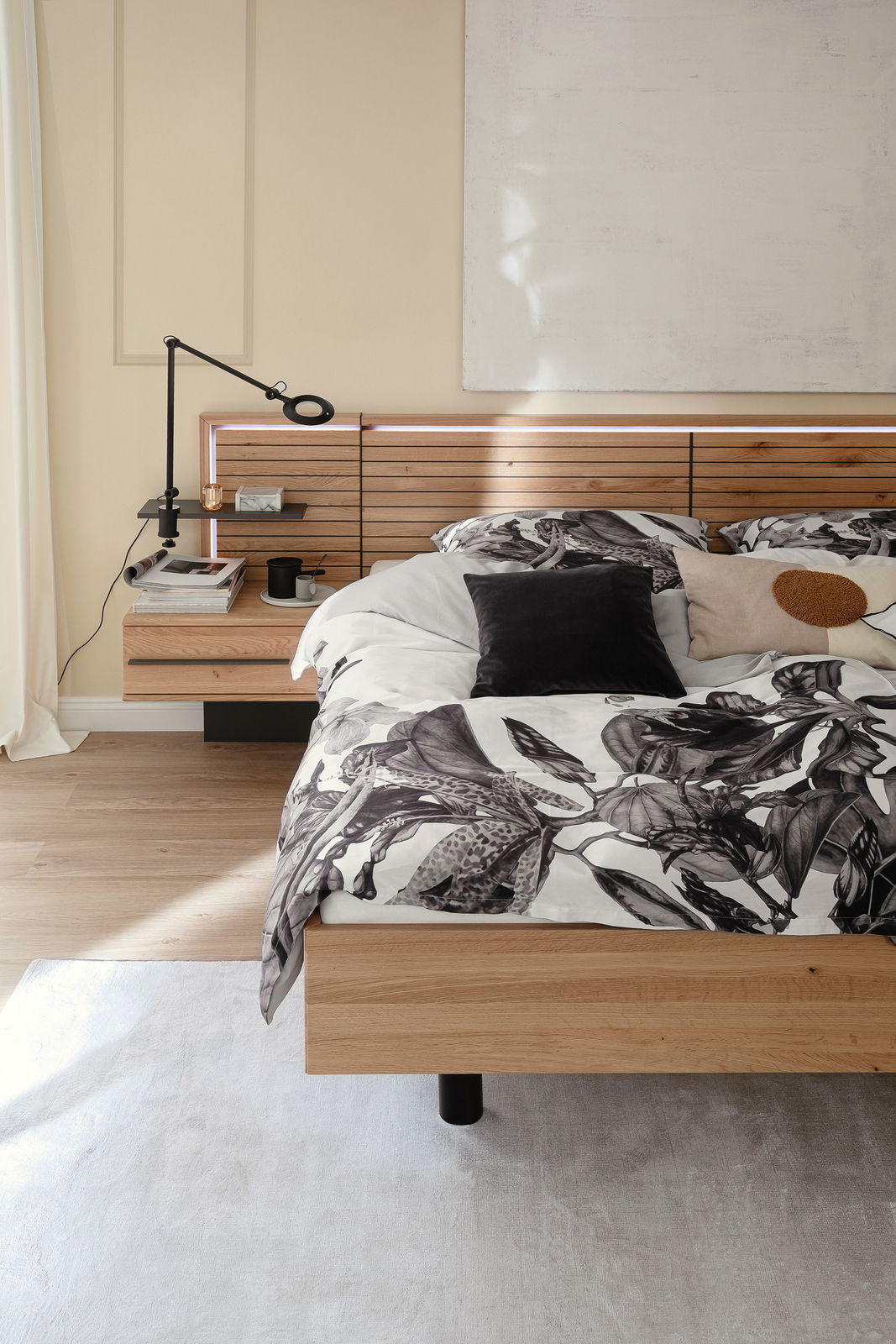 Satin-Bettwäsche AMALIA in einem modernen Schlafzimmer, mit floralem Muster in Schwarz-Weiß, auf einem Holzrahmenbett, seitliche Perspektive.