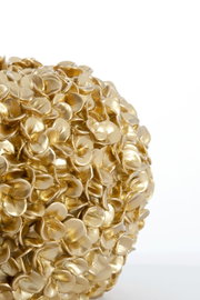 Nahaufnahme einer goldenen Vase mit blütenförmiger Struktur, seitliche Perspektive.
