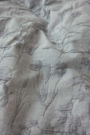 Nahaufnahme einer Bettwäsche mit floralen Mustern in Grau, leicht strukturiert.