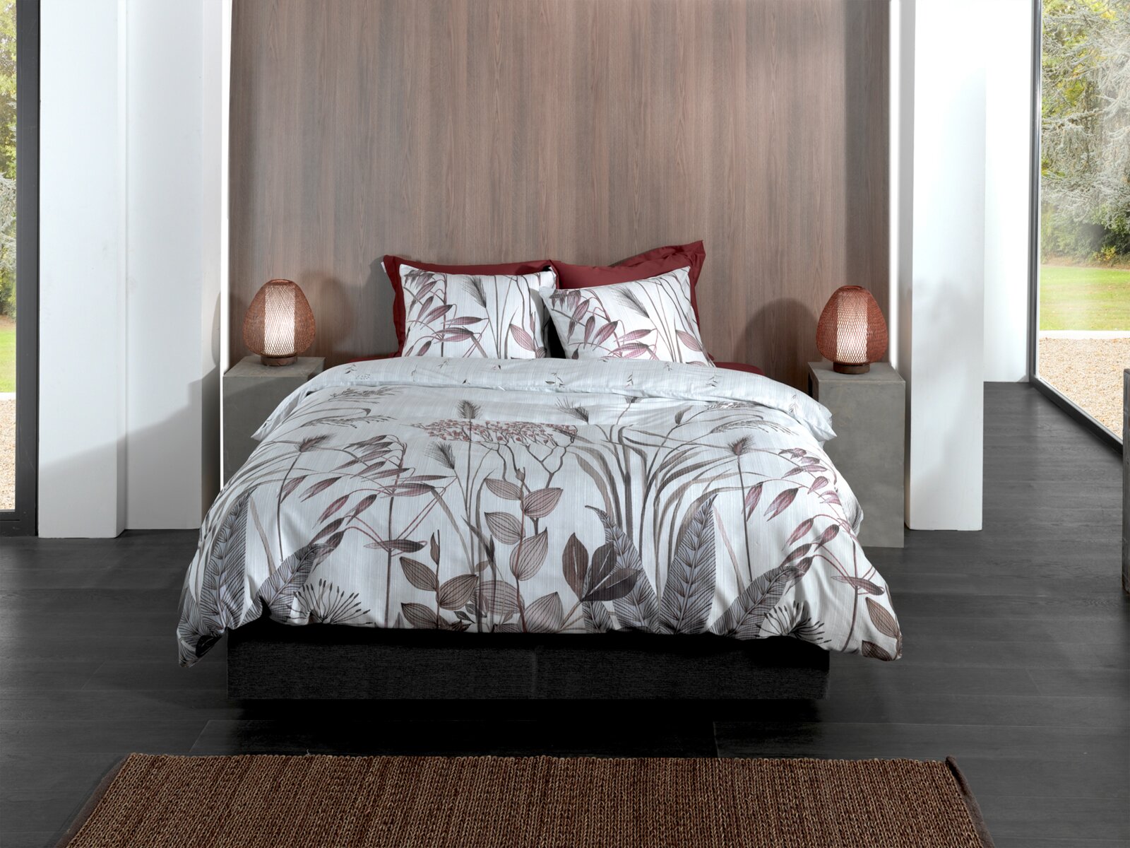 Bett mit floraler Bettwäsche in einem modernen Schlafzimmer, frontal fotografiert.