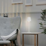 Moderne Akku-Tischleuchte EURIA in einem gemütlichen Wohnzimmer, seitliche Perspektive.