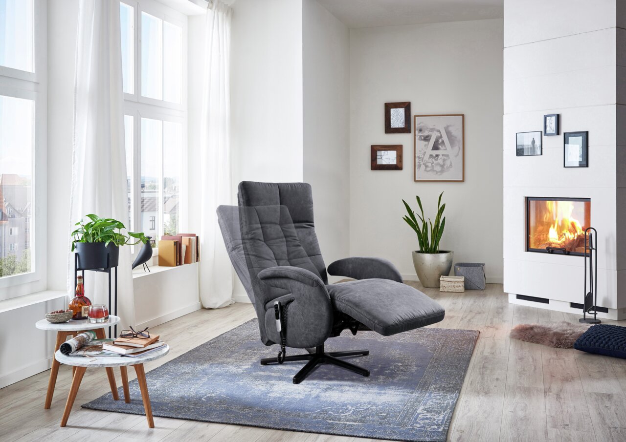 Grauer Sessel in einem modernen Wohnzimmer mit Kamin, von der Seite betrachtet.