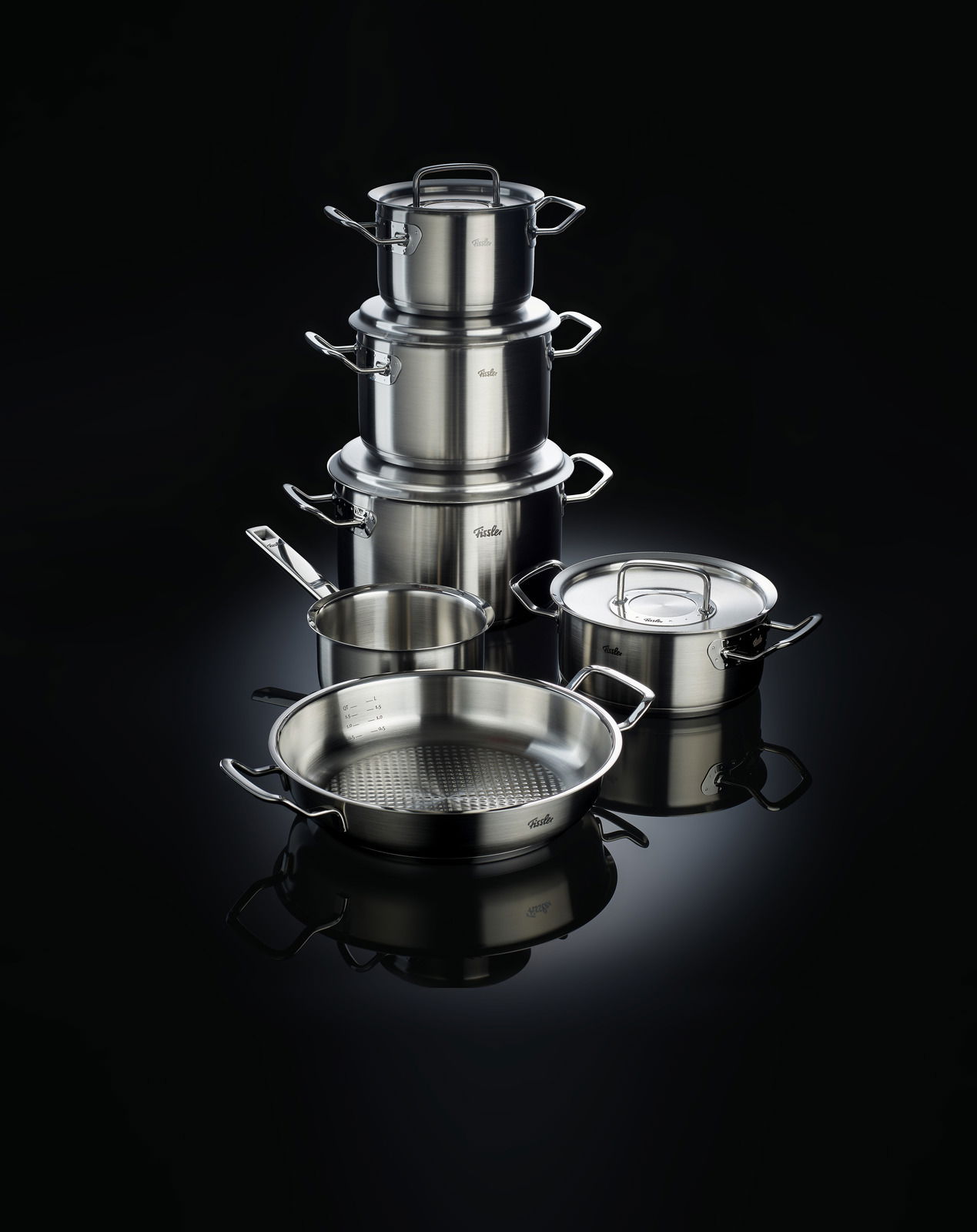 Topfset Original-Profi 5-teilig, bestehend aus mehreren Edelstahltöpfen und Pfannen, auf schwarzem Hintergrund, seitliche Perspektive.