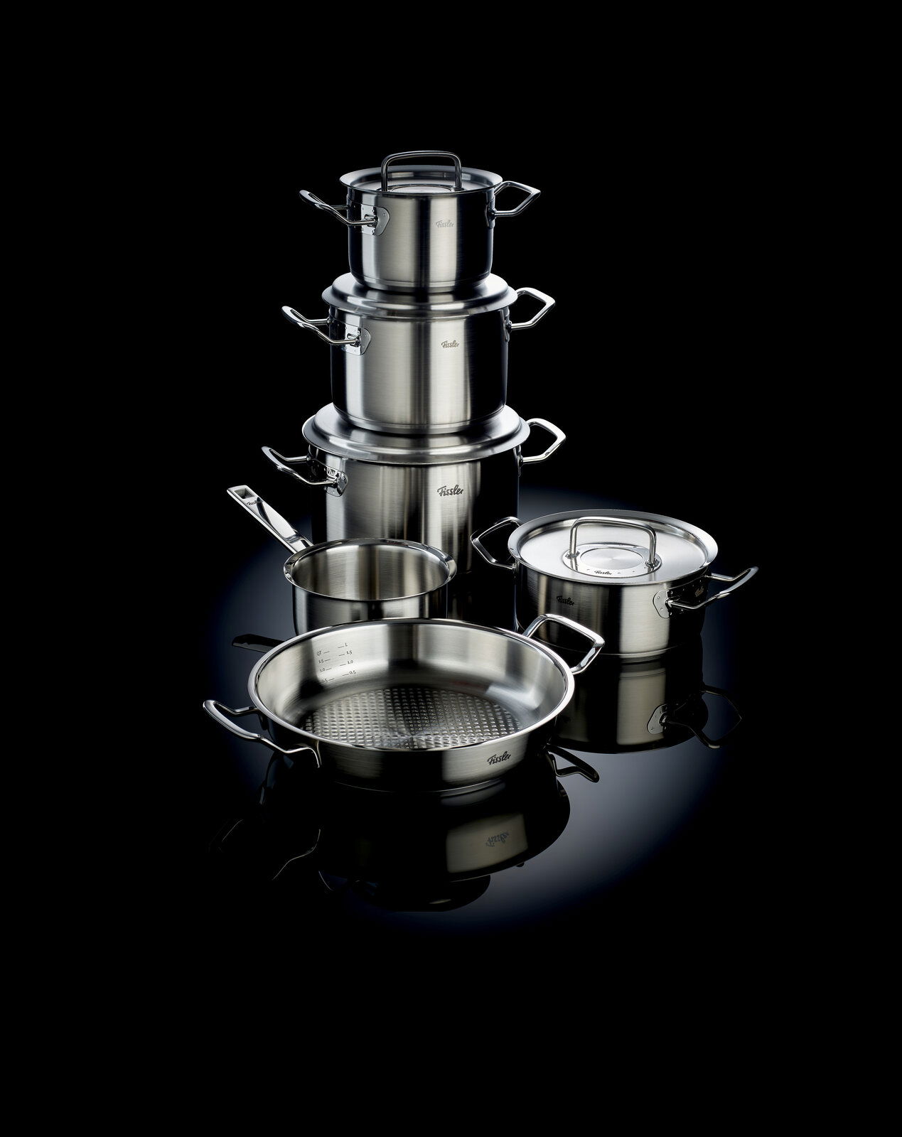 Topfset Original-Profi 5-teilig, bestehend aus mehreren Edelstahltöpfen und Pfannen, auf schwarzem Hintergrund, seitliche Perspektive.