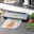 Vakuumiergerät auf einer Küchenarbeitsplatte, frontal fotografiert, mit vakuumiertem Lachsfilet und frischem Gemüse im Hintergrund.