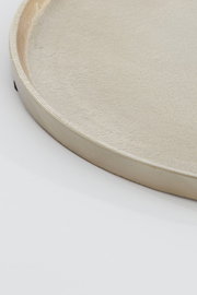 Nahaufnahme einer runden, flachen Schale mit glatter, metallischer Oberfläche, seitliche Perspektive.