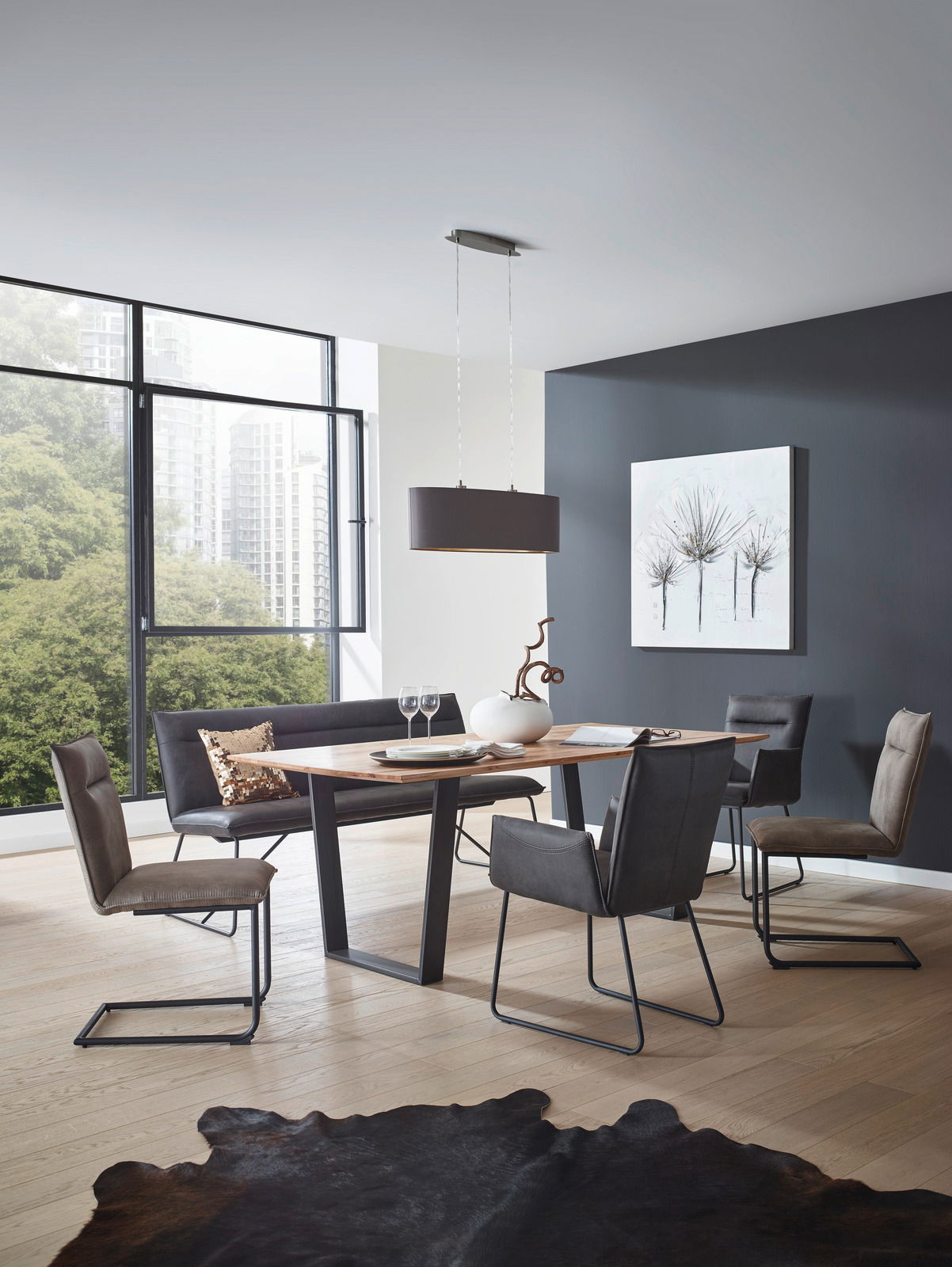 Valnatura Bank SCALA Moderner Essbereich mit einem rechteckigen Holztisch und vier Freischwinger-Stühlen in einem hellen Raum mit großen Fenstern, seitliche Perspektive.