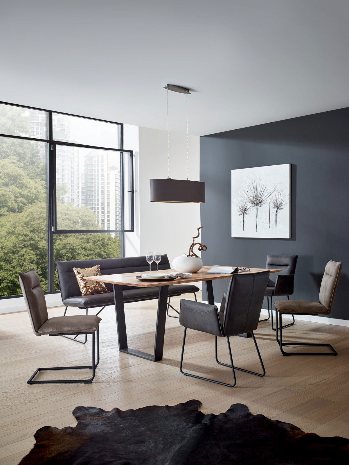 Moderner Essbereich mit einem rechteckigen Holztisch und vier Freischwinger-Stühlen in einem hellen Raum mit großen Fenstern, seitliche Perspektive.