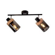 Moderne Deckenleuchte mit zwei schwenkbaren Spot-Strahlern, schwarze Metall-Schiene, Holzdetails und rauchgrauen Glaszylindern mit warm leuchtenden Filament-Lampen, fotografiert in leicht schräger Untersicht an der Decke