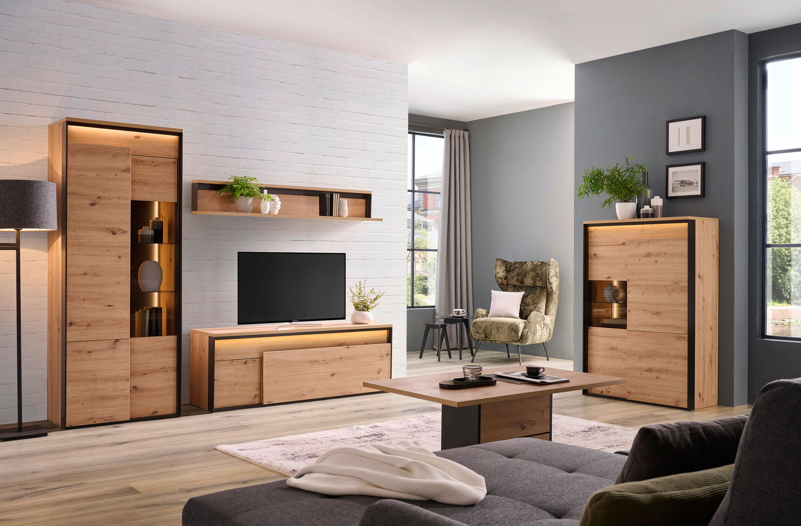 Wohnzimmer mit modernen Holzmöbeln, darunter ein TV-Lowboard, ein Wandboard, ein Highboard und ein Couchtisch, aus einer frontalen Perspektive.