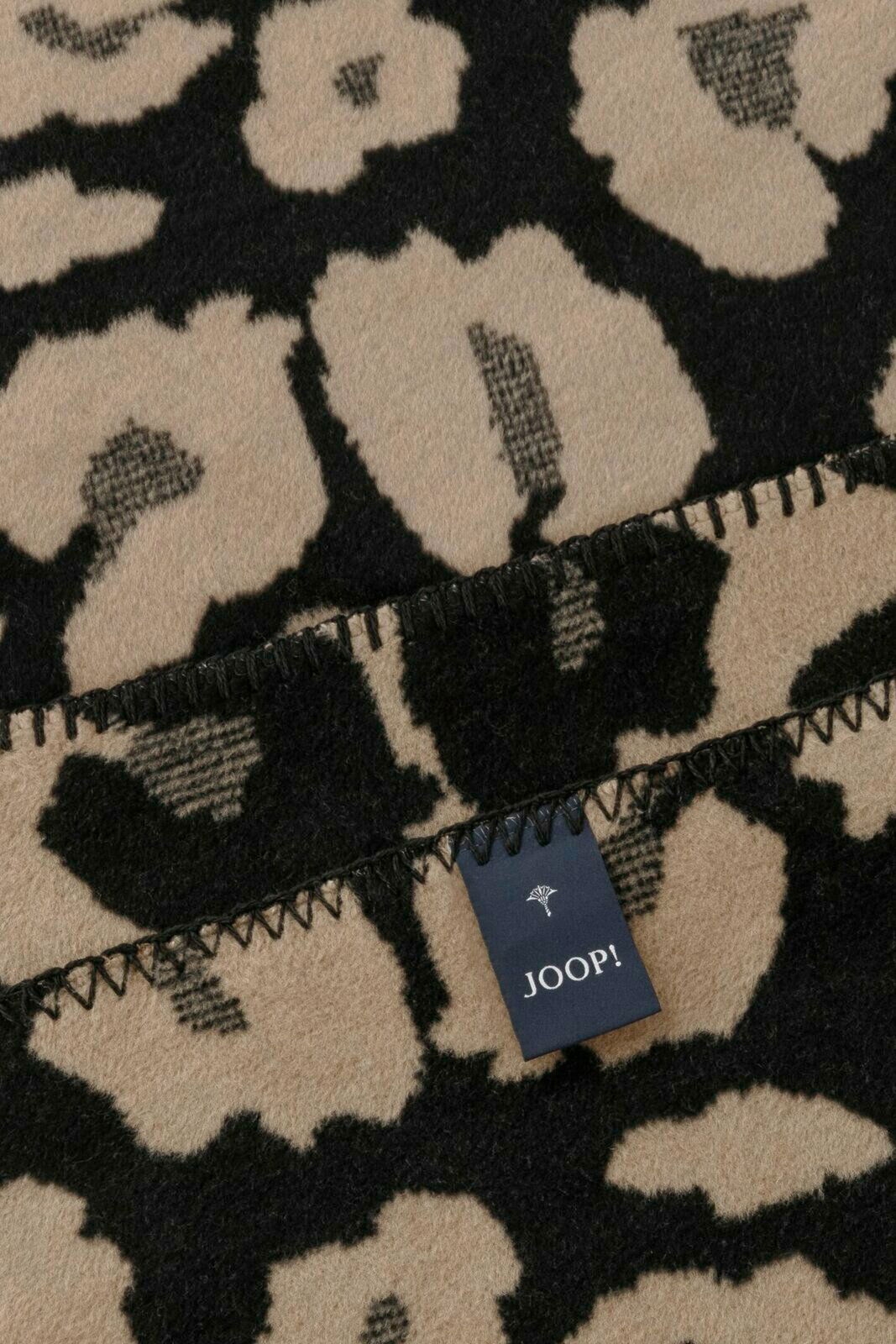 Nahaufnahme einer JOOP! Wohndecke mit Leopardenmuster in Beige und Schwarz, Etikett sichtbar.