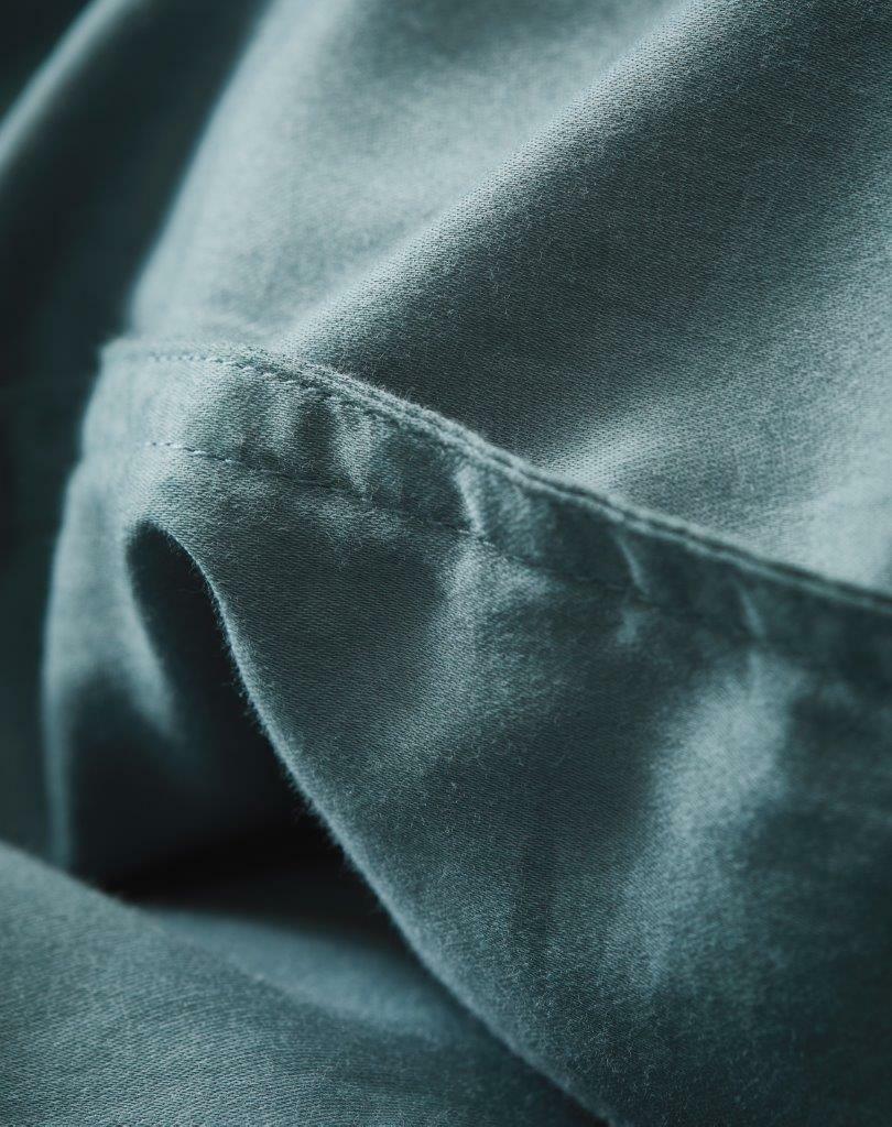 Nahaufnahme von weicher, blauer Bettwäsche mit feiner Naht, seitliche Perspektive