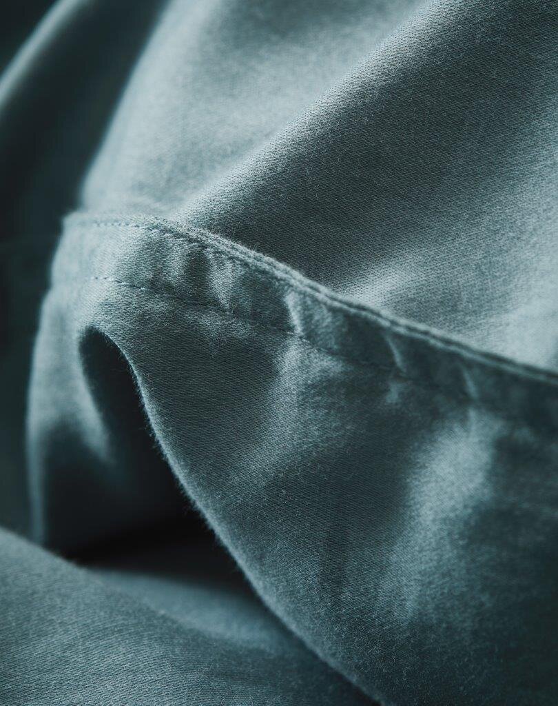 Nahaufnahme von weicher, blauer Bettwäsche mit feiner Naht, seitliche Perspektive