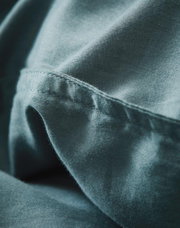 Nahaufnahme von weicher, blauer Bettwäsche mit feiner Naht, seitliche Perspektive
