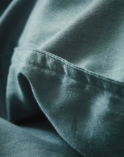 Nahaufnahme von weicher, blauer Bettwäsche mit feiner Naht, seitliche Perspektive