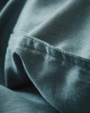 Nahaufnahme von weicher, blauer Bettwäsche mit feiner Naht, seitliche Perspektive