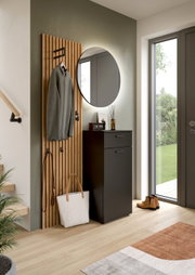 Moderner Flur mit schwarzem Schuhschrank und rundem Wandspiegel neben Holz-Lamellen-Garderobe mit Haken; Aufnahme in leicht schräger Frontalperspektive.