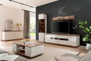 Modernes Wohnzimmer mit weißer Wohnwand und Couchtisch in Holzoptik, TV-Board mit Fernseher, Vitrine und Sideboard vor dunkler Akzentwand, aufgenommen aus schräger Frontperspektive auf Augenhöhe.