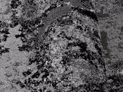 Nahaufnahme eines grauen Teppichs mit abstraktem Muster, perspektivisch von der Seite aufgenommen.