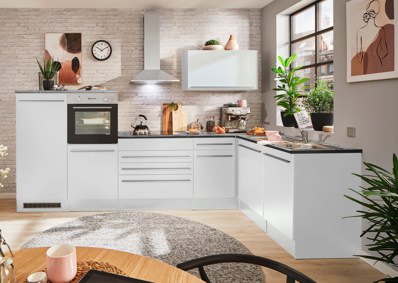 Moderne weiße Küche mit Eckunterschrank, Backofen, Herd und Spüle, aus der Perspektive eines Esszimmers mit Blick auf die Arbeitsfläche und Fenster.