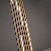 Nahaufnahme einer modernen LED-Stehleuchte mit vertikalen Holzstreben und integrierten Leuchtstreifen, seitliche Perspektive.