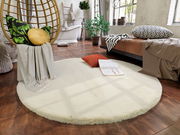 Runder, cremefarbener Fellteppich in einem gemütlichen Schlafzimmer mit Holzboden, neben einem Hängesessel und einem Bett, aus der Vogelperspektive betrachtet.