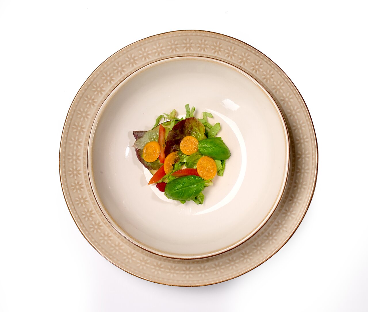 Beiger Teller Omara 20cm mit floralem Muster, von oben fotografiert, serviert mit einem frischen Salat.