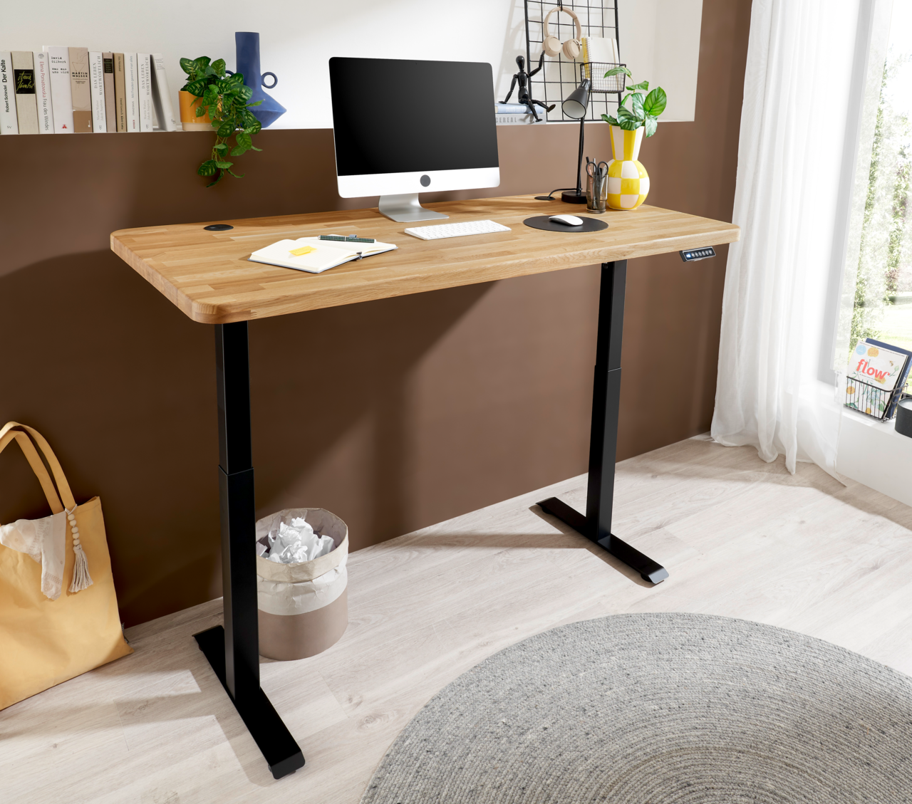 Moderner E-Schreibtisch mit Holzplatte und schwarzem Gestell, seitliche Perspektive, ausgestattet mit Computer und Pflanzen.