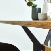 Nahaufnahme eines Esstisches mit Holzplatte und Metallgestell, seitliche Perspektive