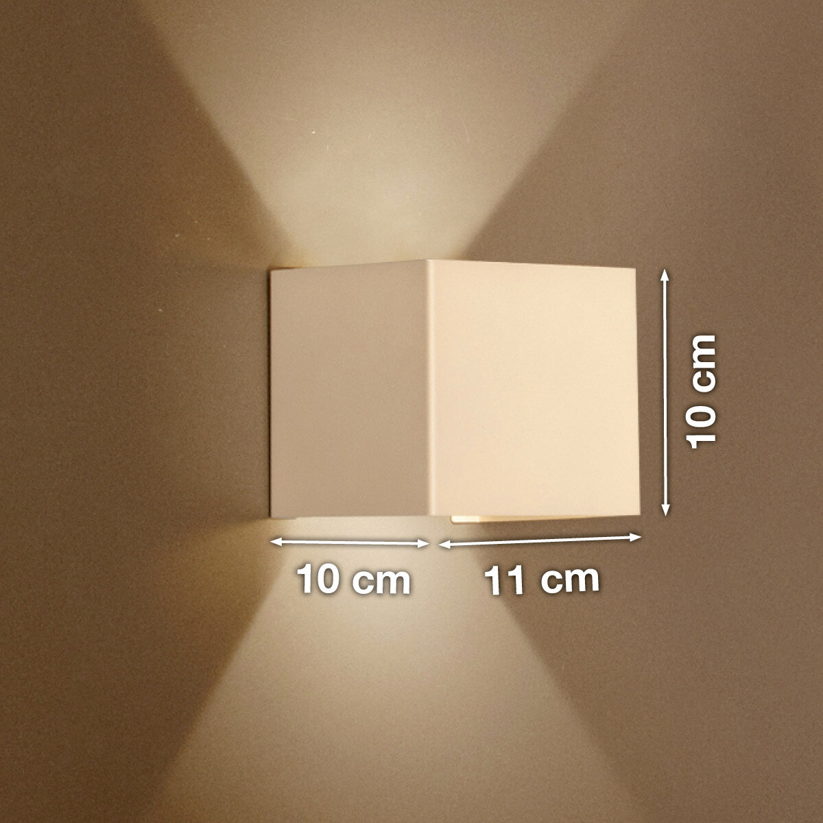 Weiße, kubische Wandleuchte mit Up-&-Downlight an beiger Wand, Lichtkegel nach oben und unten, Maße ca. 10 cm hoch, 10 cm tief und 11 cm breit, Frontansicht leicht seitlich.